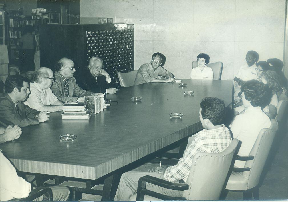 Foto de  Olga Vega, en la cabecera de la mesa, durante la visita de Nicolás Guillén a la BNCJM, 3 de marzo de 1981. Fondos BNCJM.